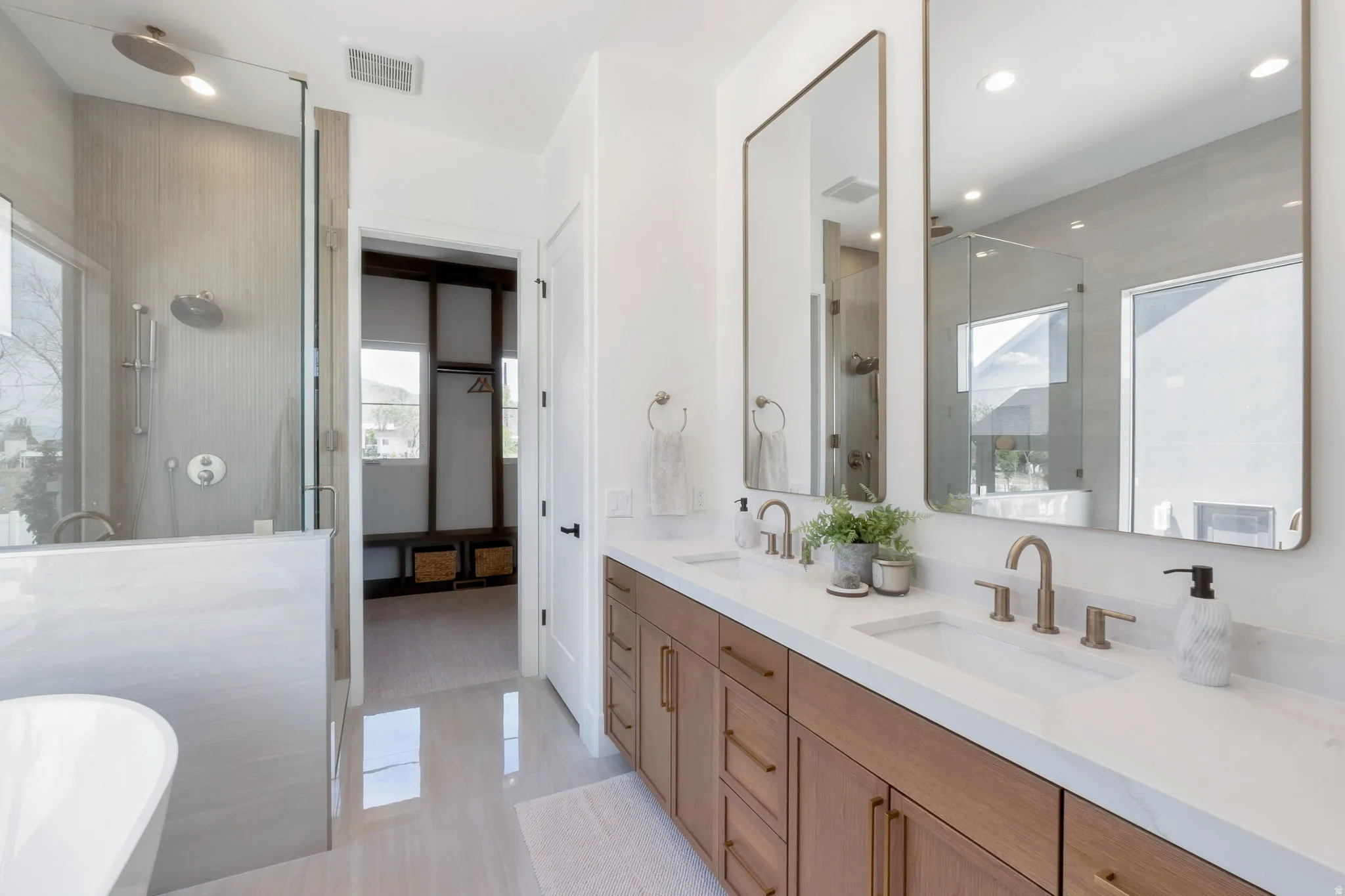 Bathroom featuring a dual vanity with wood-finish cabinetry, white countertops, and contemporary rectangular sinks