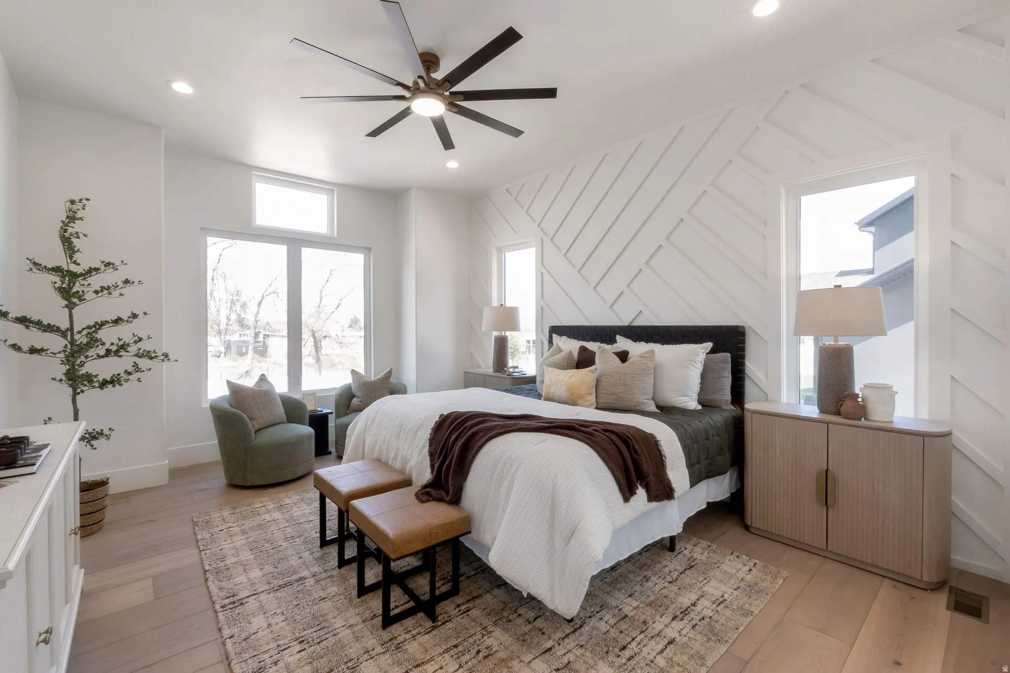 Spacious room featuring light wood-finish flooring, a decorative accent wall, and multiple large windows