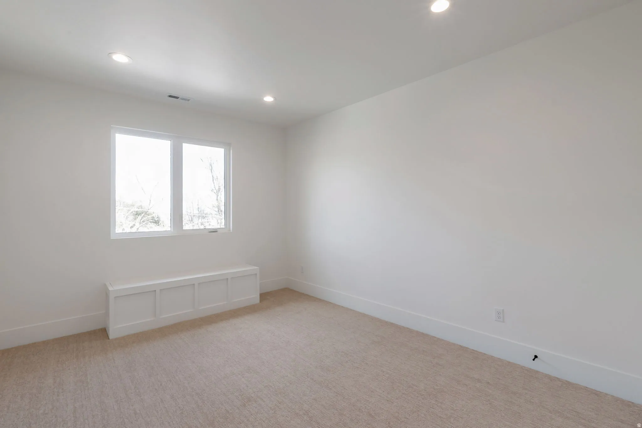 Bright room featuring a window with a built-in window seat, recessed lighting, neutral carpet, and white baseboards