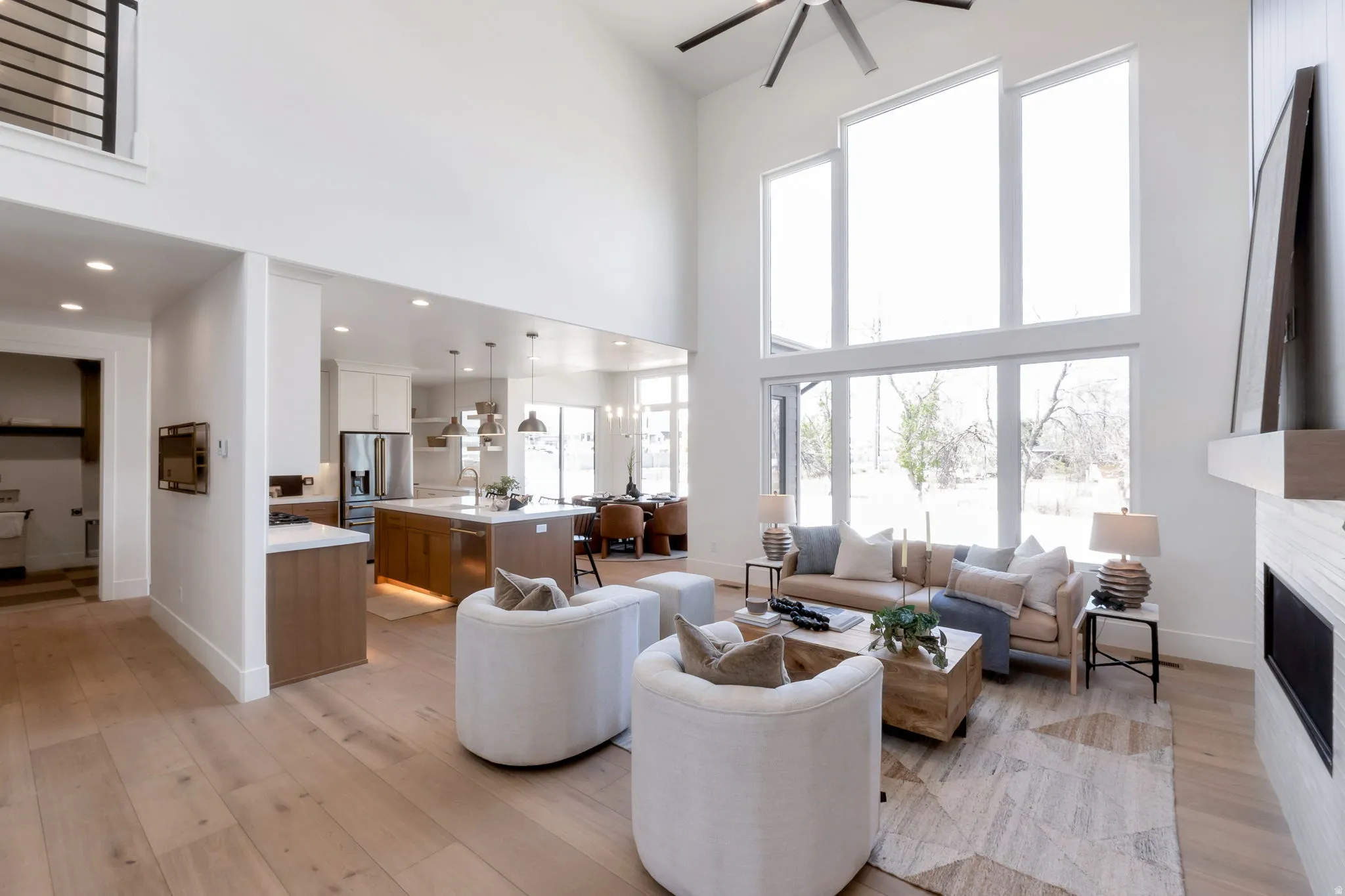 Spacious living area featuring double-height ceilings, a prominent fireplace, and large windows