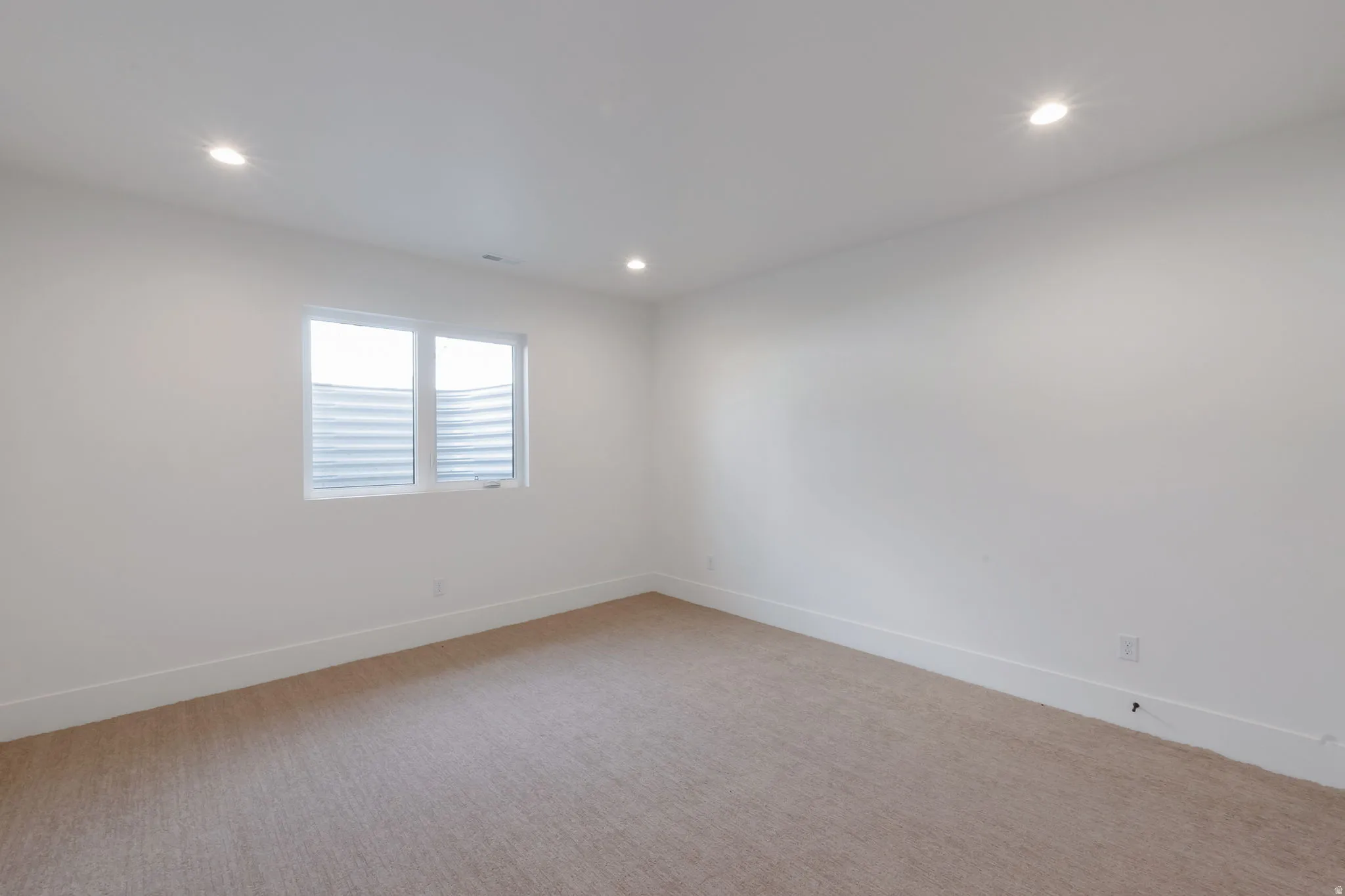 Carpeted room featuring white walls, recessed lighting, and a single window with horizontal blinds