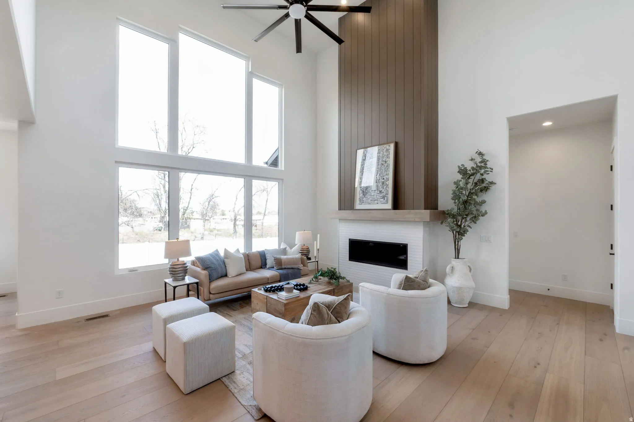 Spacious living area featuring double-height ceilings, a contemporary linear fireplace with a white tile surround, and expansive windows