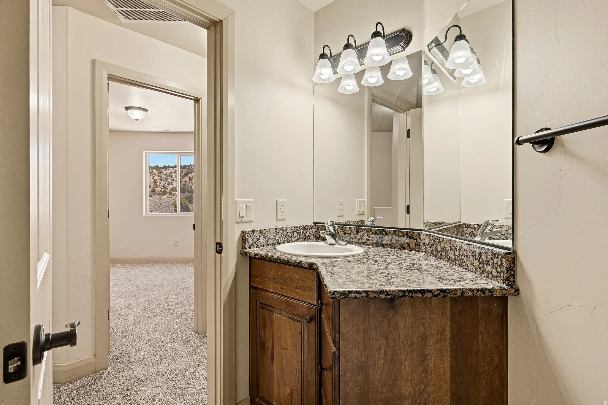 Bathroom vanity featuring a granite-style countertop, undermount sink, and wood-finish cabinetry