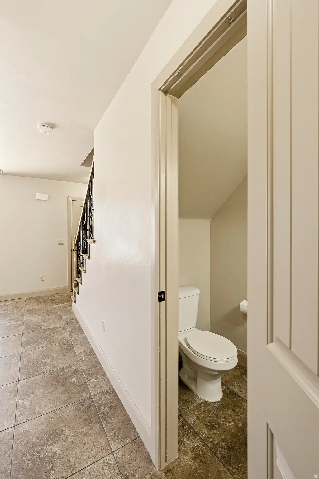 Powder room featuring a white toilet and coordinating floor tiling