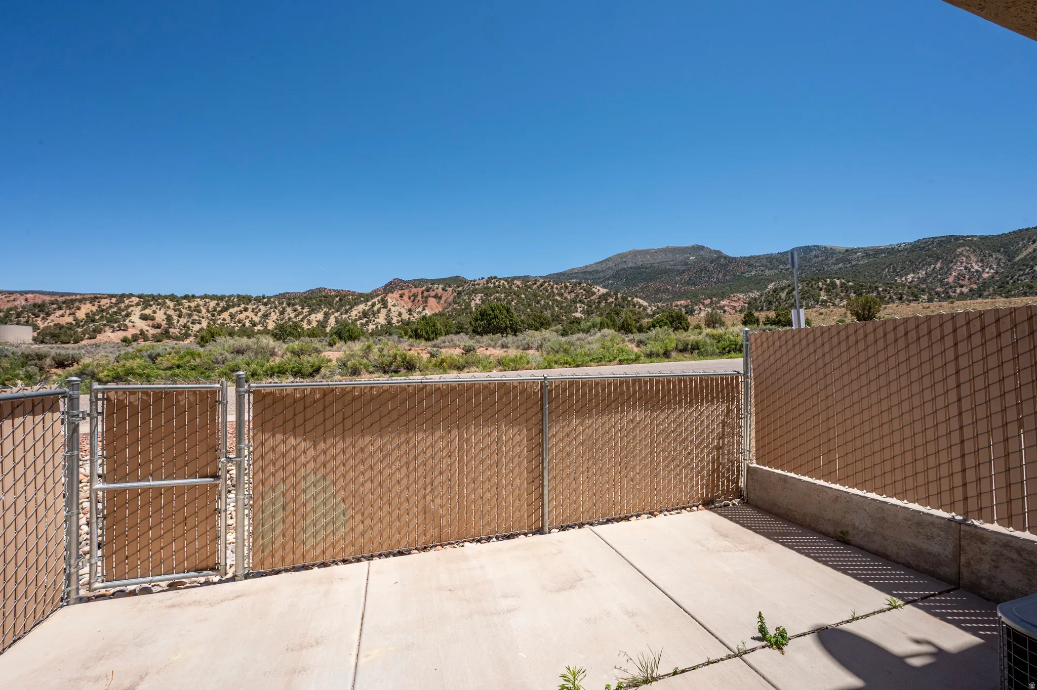 Outdoor concrete patio with chain-link fencing, privacy slats, and a gate