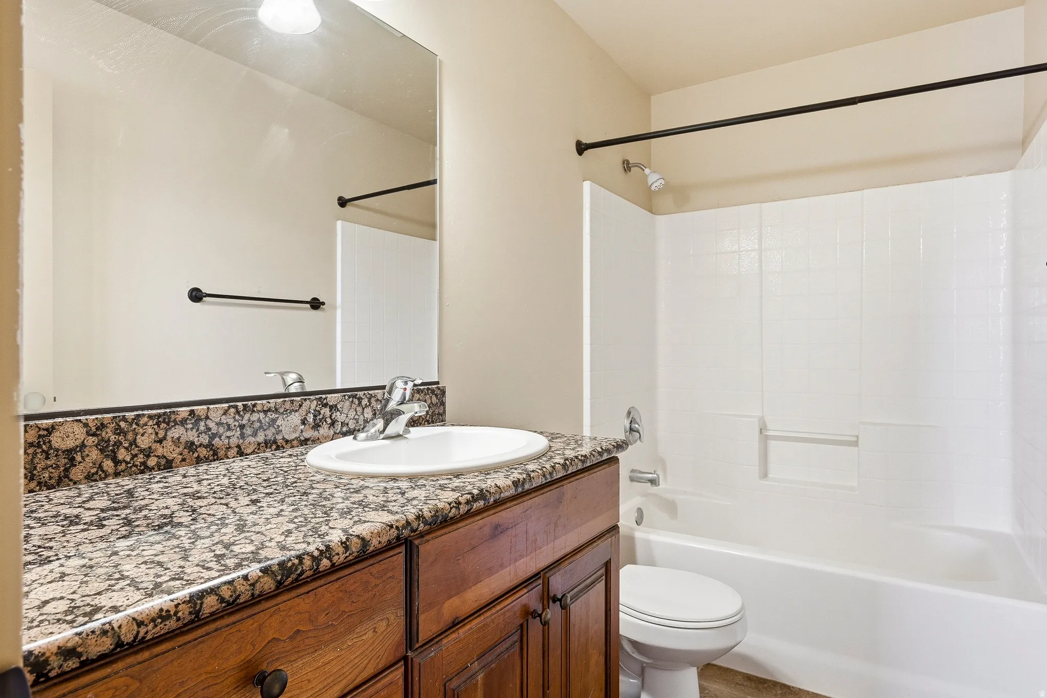 Bathroom featuring a vanity with a granite-style countertop, an undermount sink, and wood-finish cabinetry