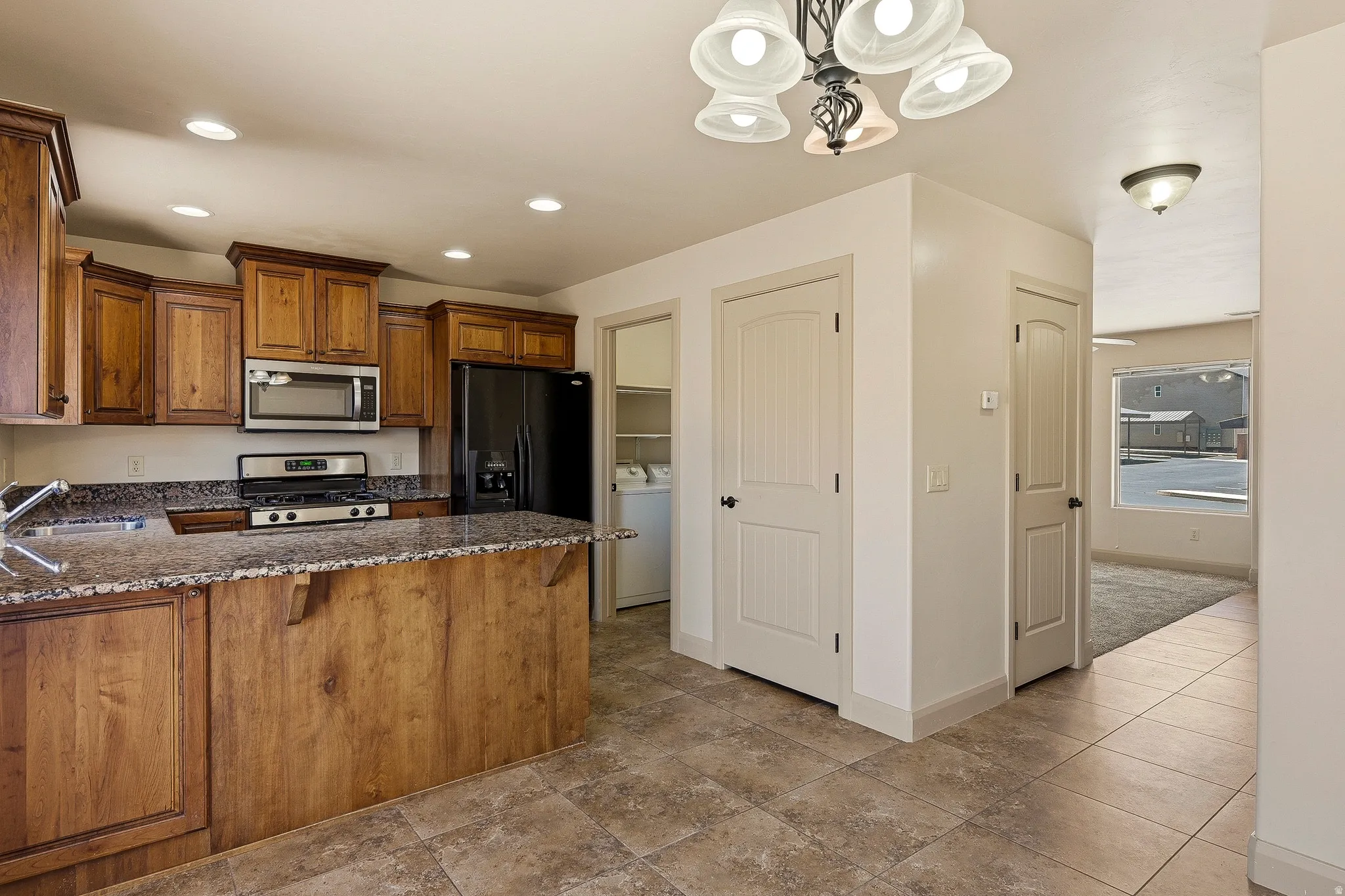 Kitchen with wood cabinetry, stainless steel appliances, and a central island with a granite countertop