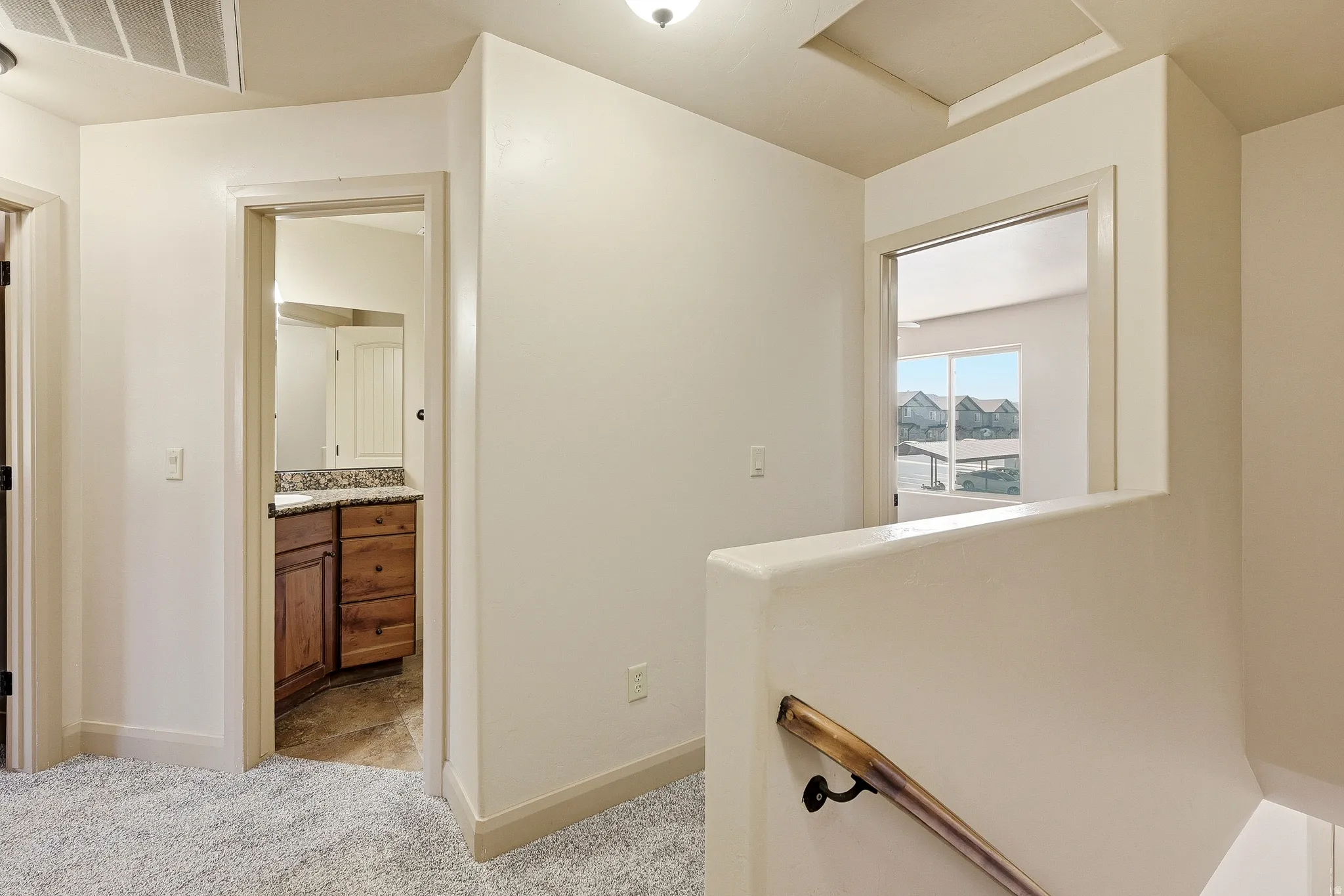 Carpeted landing with a wood handrail leading to an open doorway
