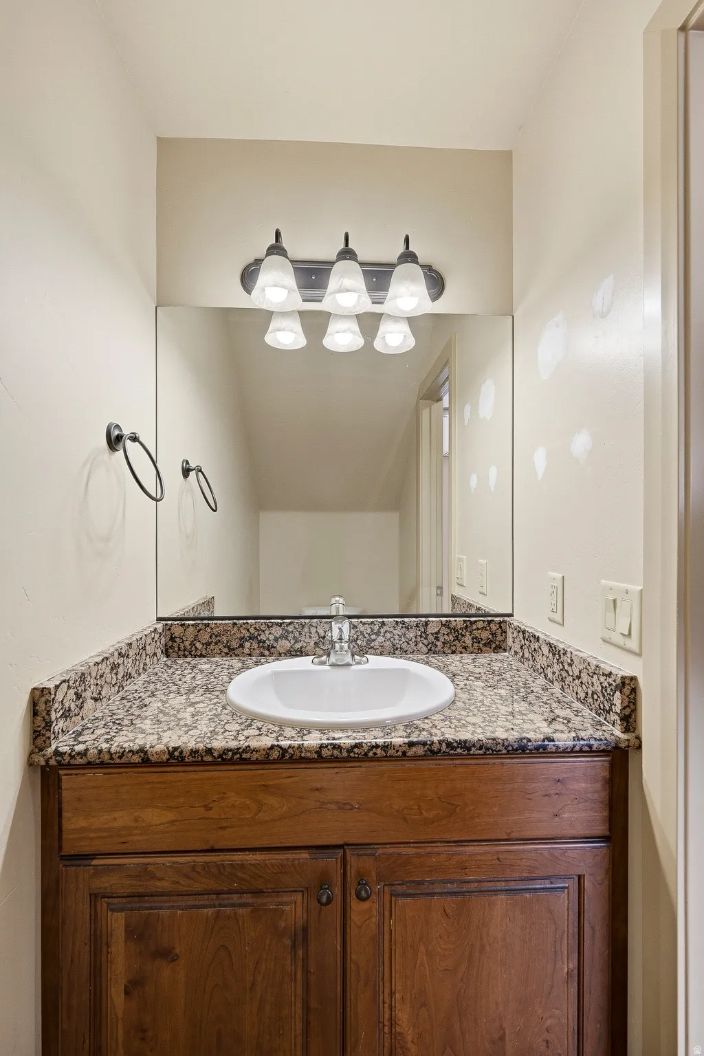 Vanity featuring a stone countertop, an undermount sink, and a chrome faucet