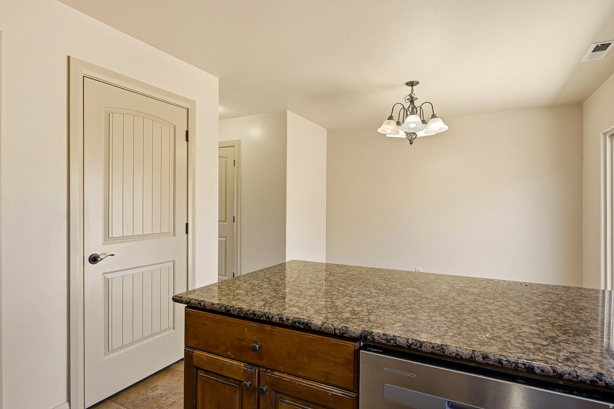 Kitchen island featuring a speckled stone countertop and integrated stainless steel dishwasher