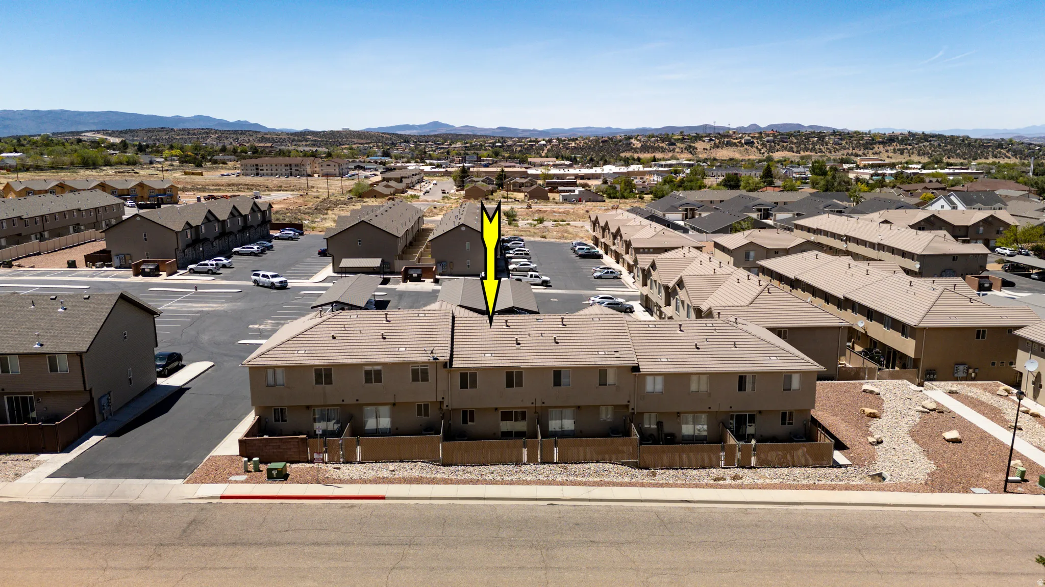 Multi-unit property featuring tan exterior siding, brown roofing, and individual patios