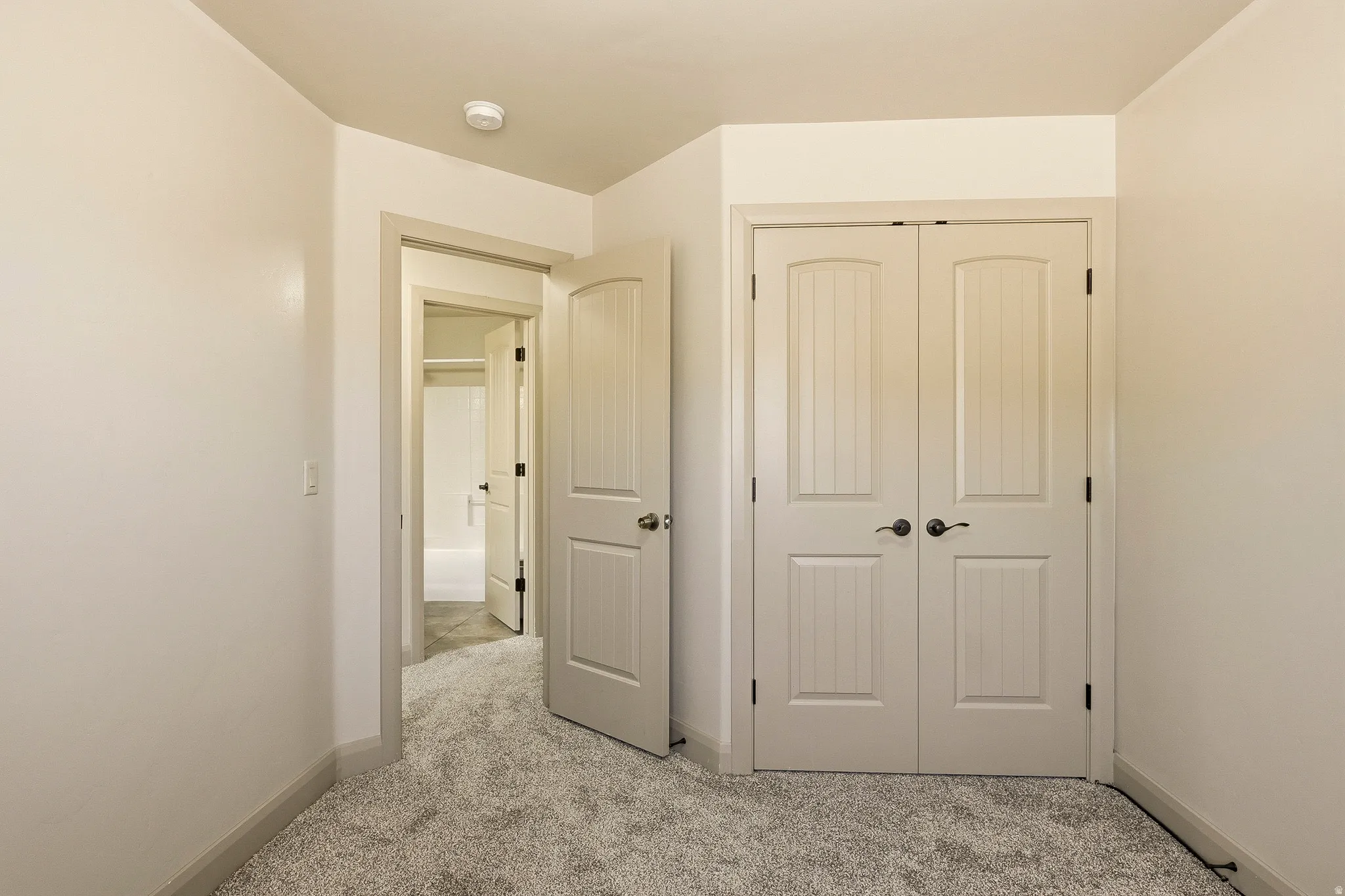 Bedroom featuring soft gray carpet, light neutral wall paint, and a built-in closet with double paneled doors
