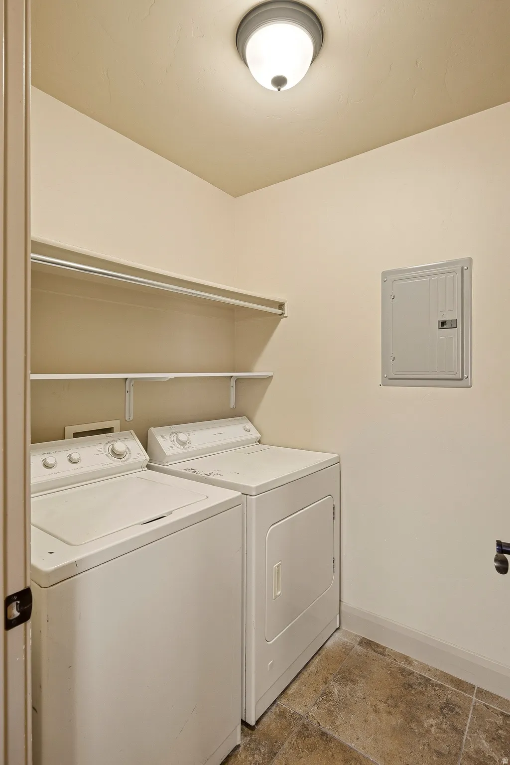 Laundry area featuring a top-load washing machine, a front-load dryer, and two wall-mounted storage shelves
