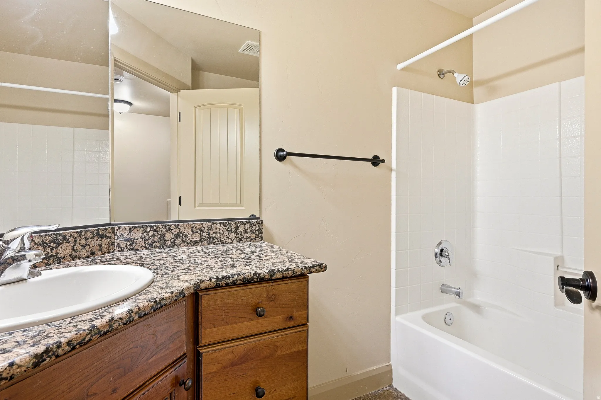 Bathroom featuring a white porcelain tub with integrated shower, chrome fixtures, and white tiled surround