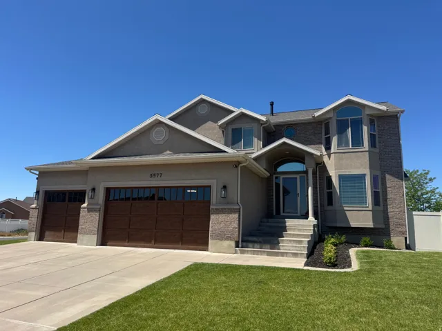 Contemporary two-story residence featuring a combination facade of brick and stucco, an arched entryway with a transom window, and a grand staircase leading to the front door