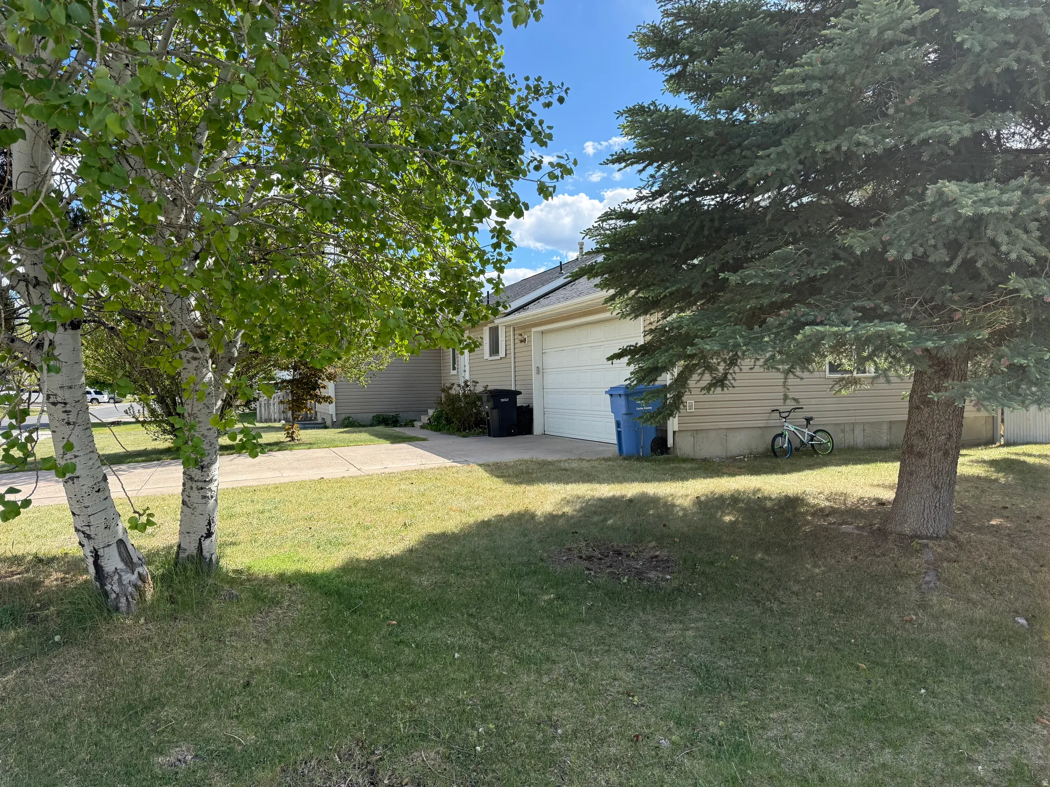 Front exterior featuring a two-car garage with a white door, light-colored siding, and a concrete driveway