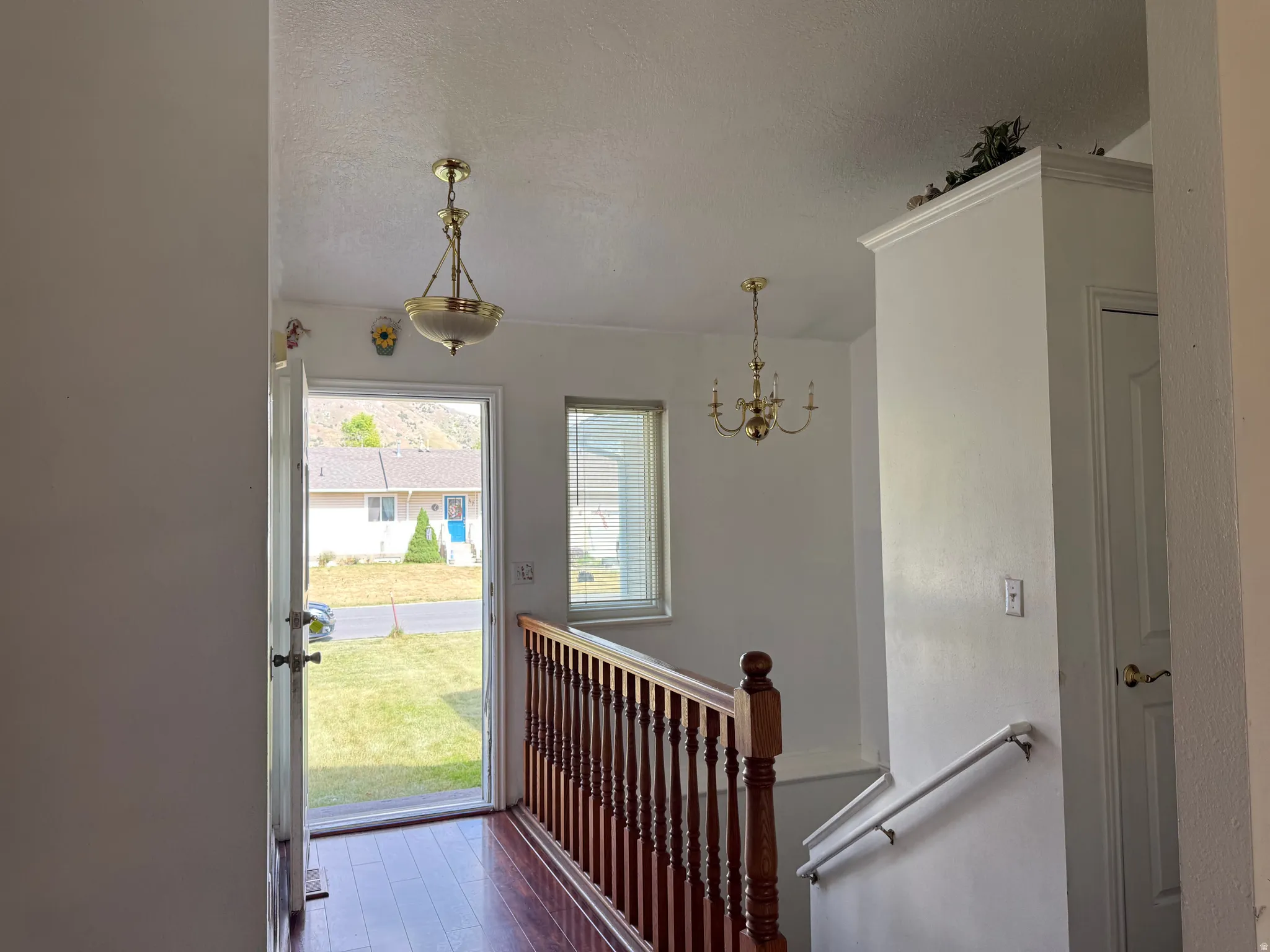 Entryway featuring hardwood-finish flooring, a brass chandelier, and a window with blinds