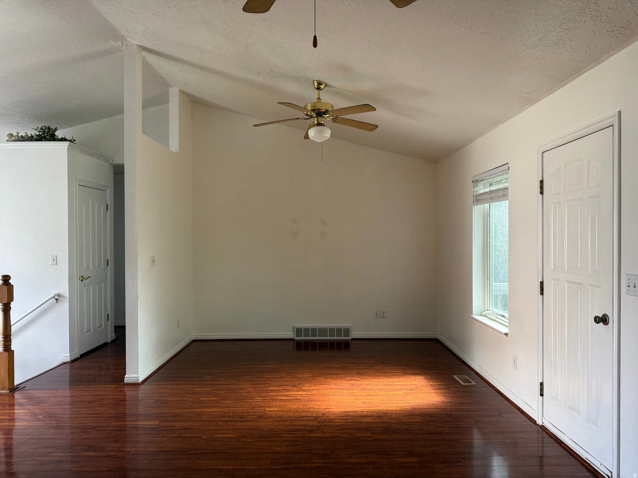 Spacious room featuring vaulted ceilings and dark wood-finish flooring