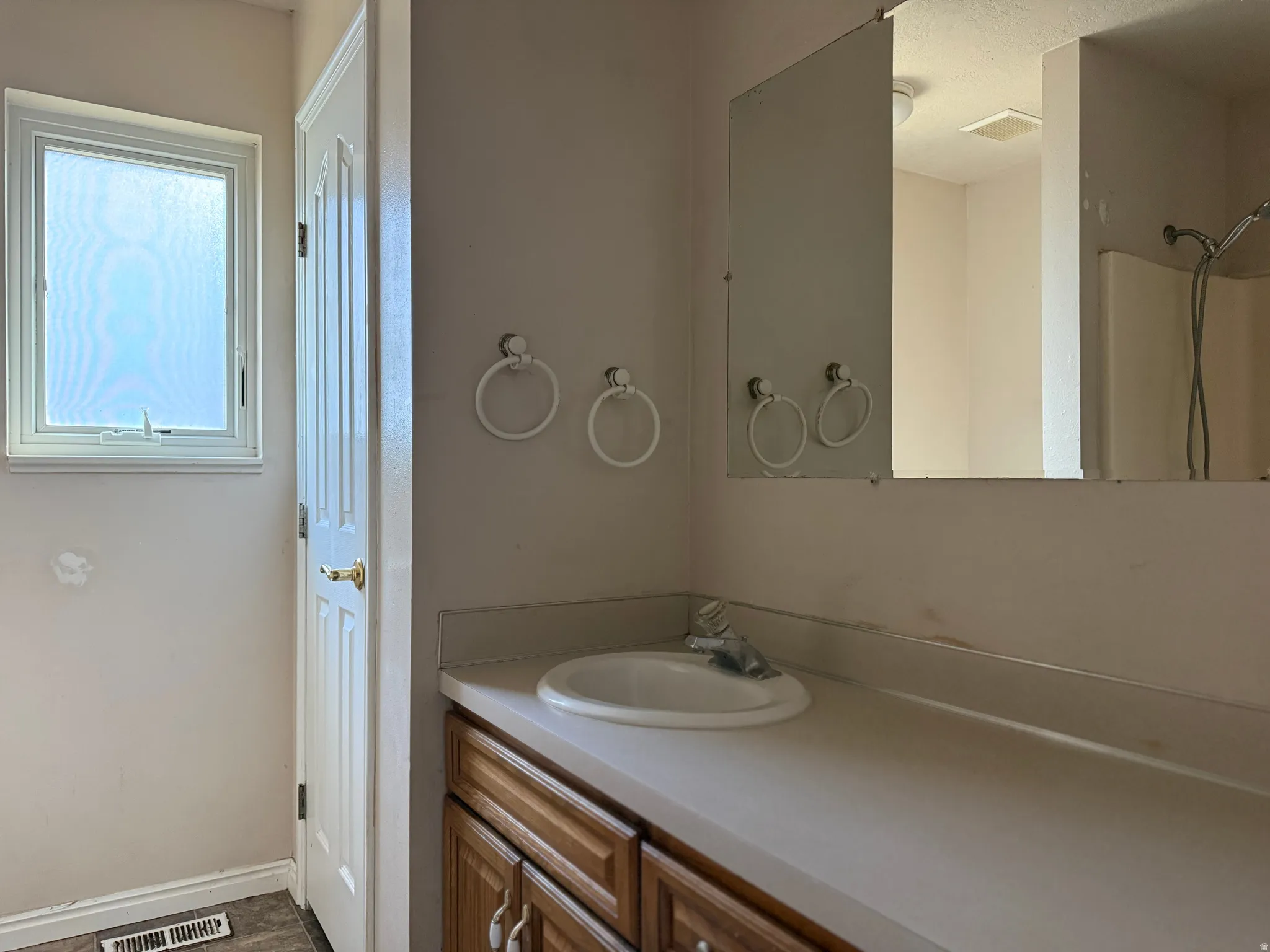 Bathroom vanity featuring a white oval sink with chrome faucet, set into a light-toned countertop