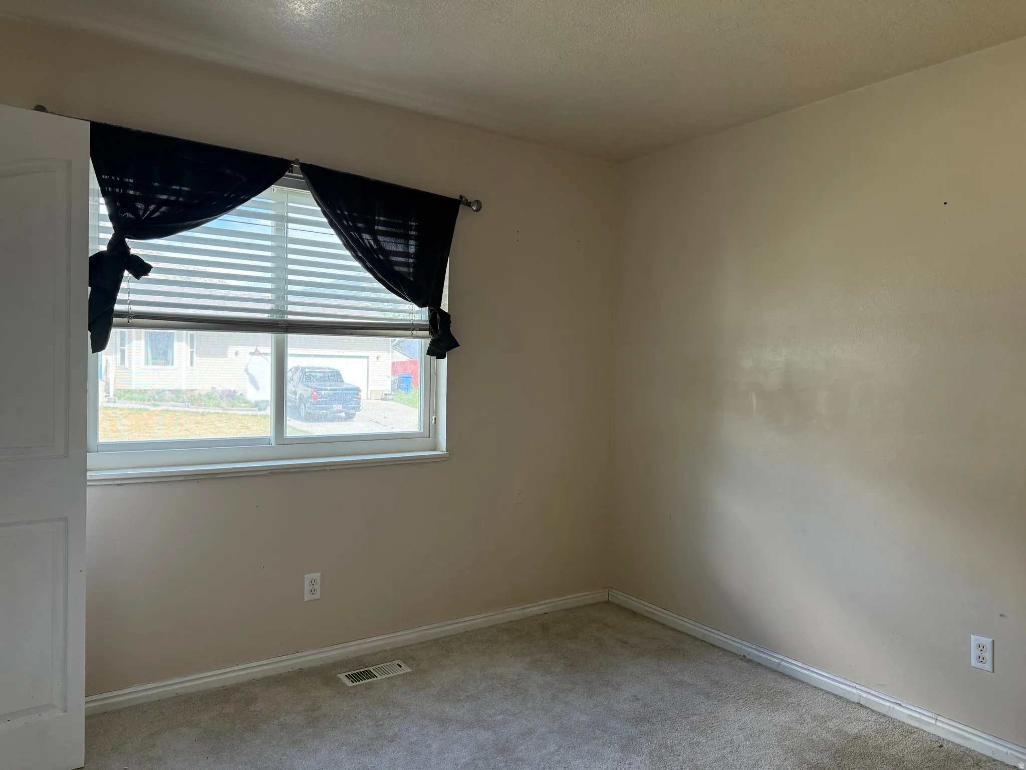 Bedroom featuring a window with horizontal blinds, neutral wall tones, and carpet flooring