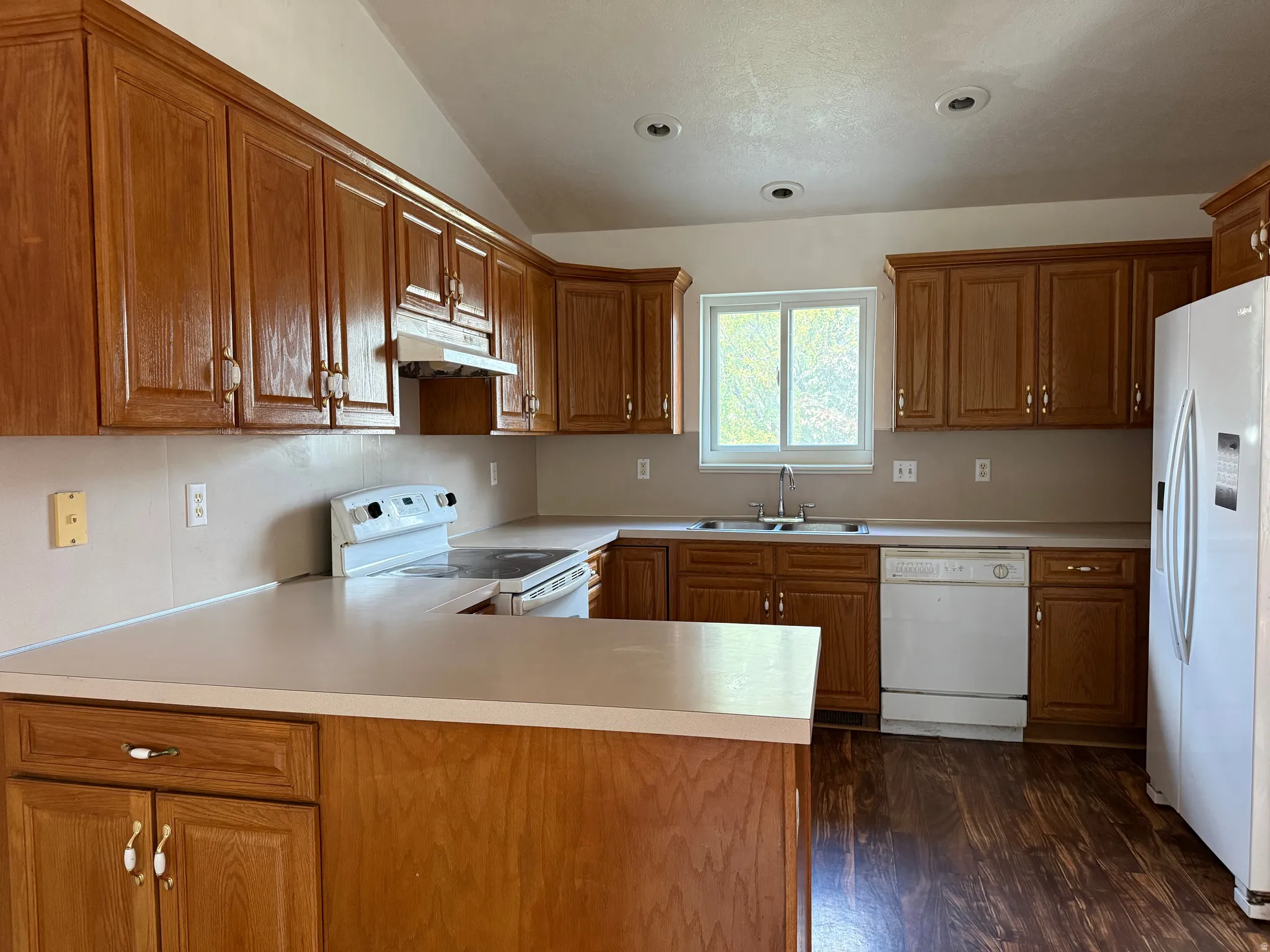 Kitchen featuring extensive wood cabinetry, laminate countertops, wood-finish flooring, a stainless-steel sink, and recessed lighting