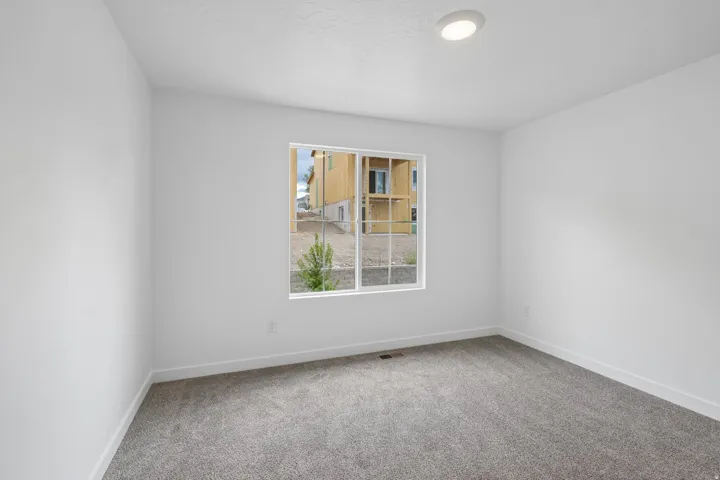 Recessed ceiling lighting, white walls, gray carpeting, and a white-framed window