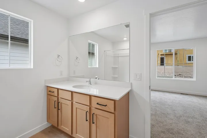 Bathroom featuring a wood-finish vanity with ample storage, a white countertop, and an integrated sink