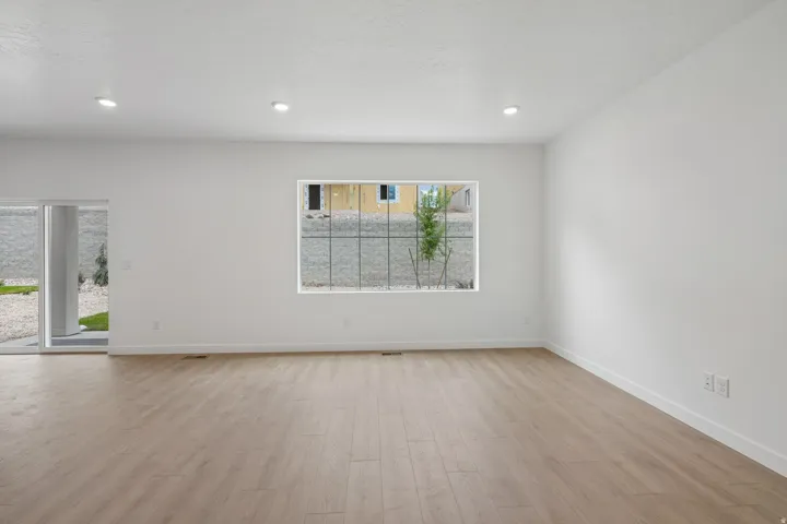 Recessed lighting, light wood-finish flooring, white walls, and a sliding glass door