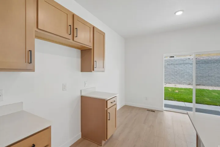 Light wood-finish cabinetry with dark hardware, light countertops, wood-finish flooring, recessed lighting, and sliding glass doors to exterior