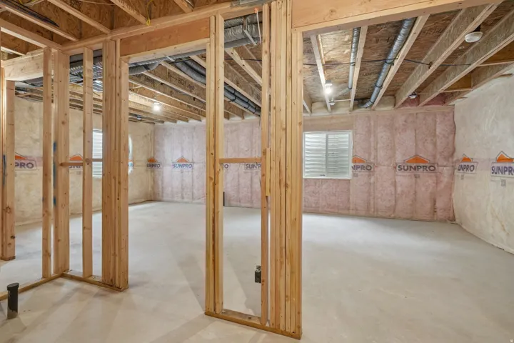 Unfinished basement featuring wood framing, concrete flooring, and insulated walls