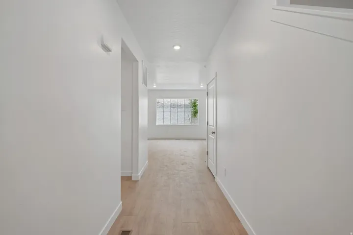 Recessed lighting, wood-finish flooring, white walls, white trim, and a white interior door