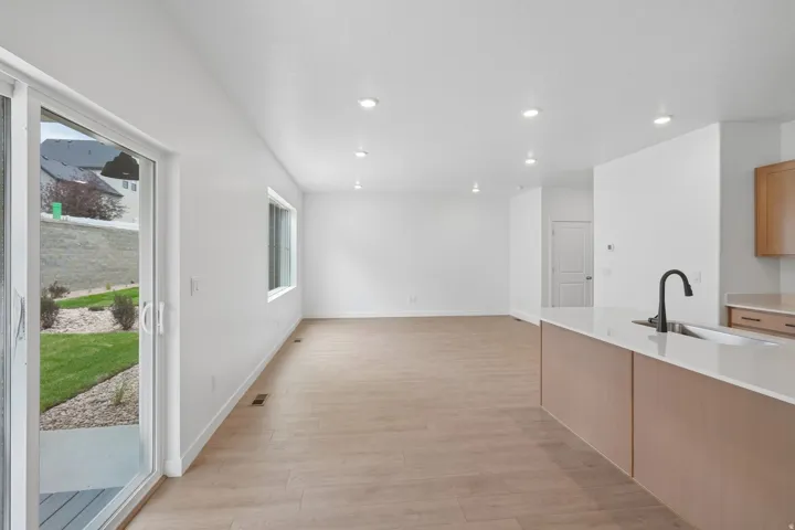 Open-concept living space featuring wood-finish flooring, recessed lighting, and a sliding glass door