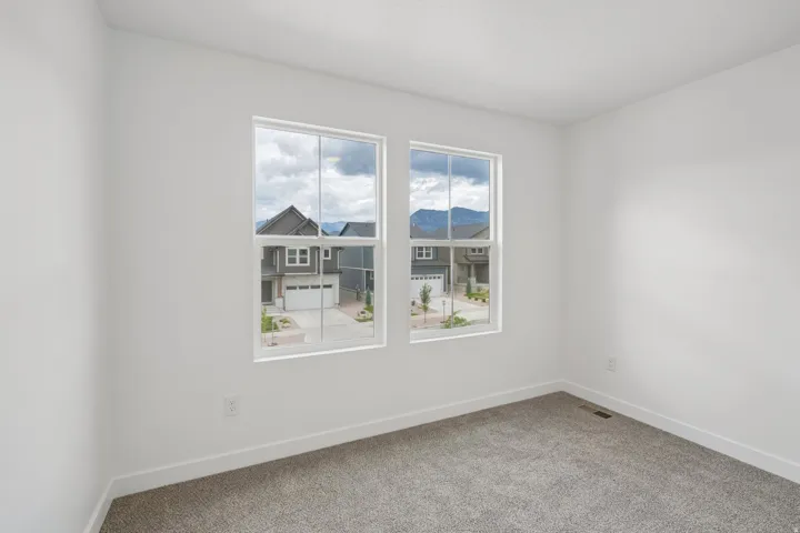 Neutral wall paint, plush carpet flooring, and two large windows