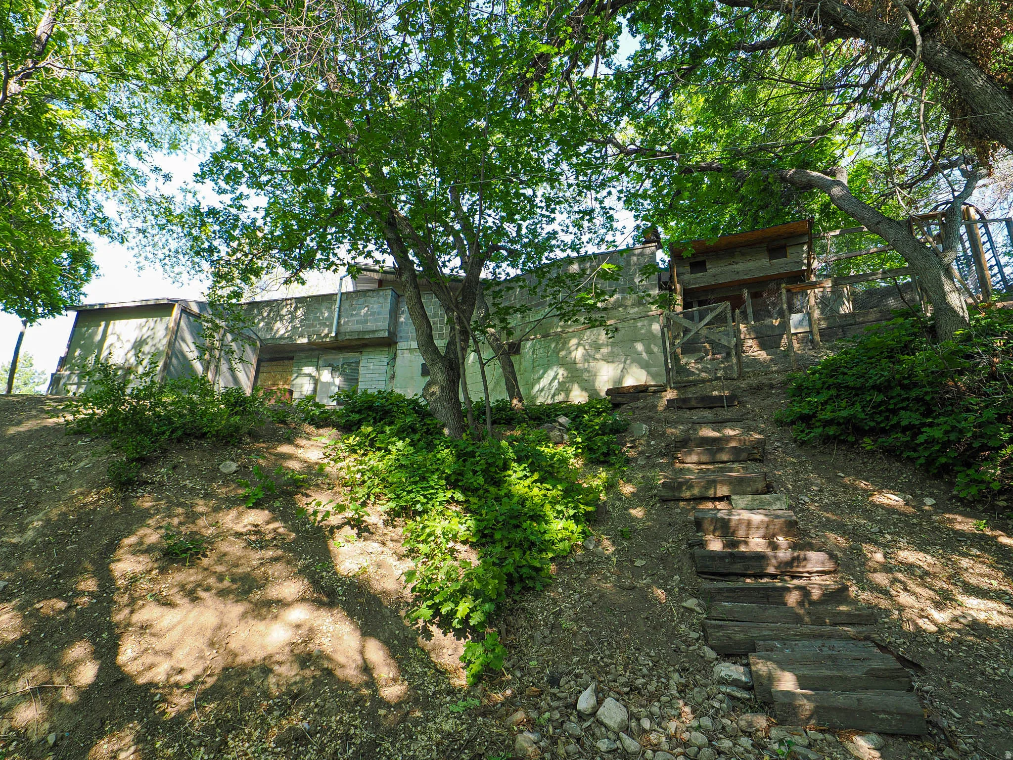 Terraced grounds with a multi-level wood staircase leading to a structure with a wood exterior and a concrete-block base