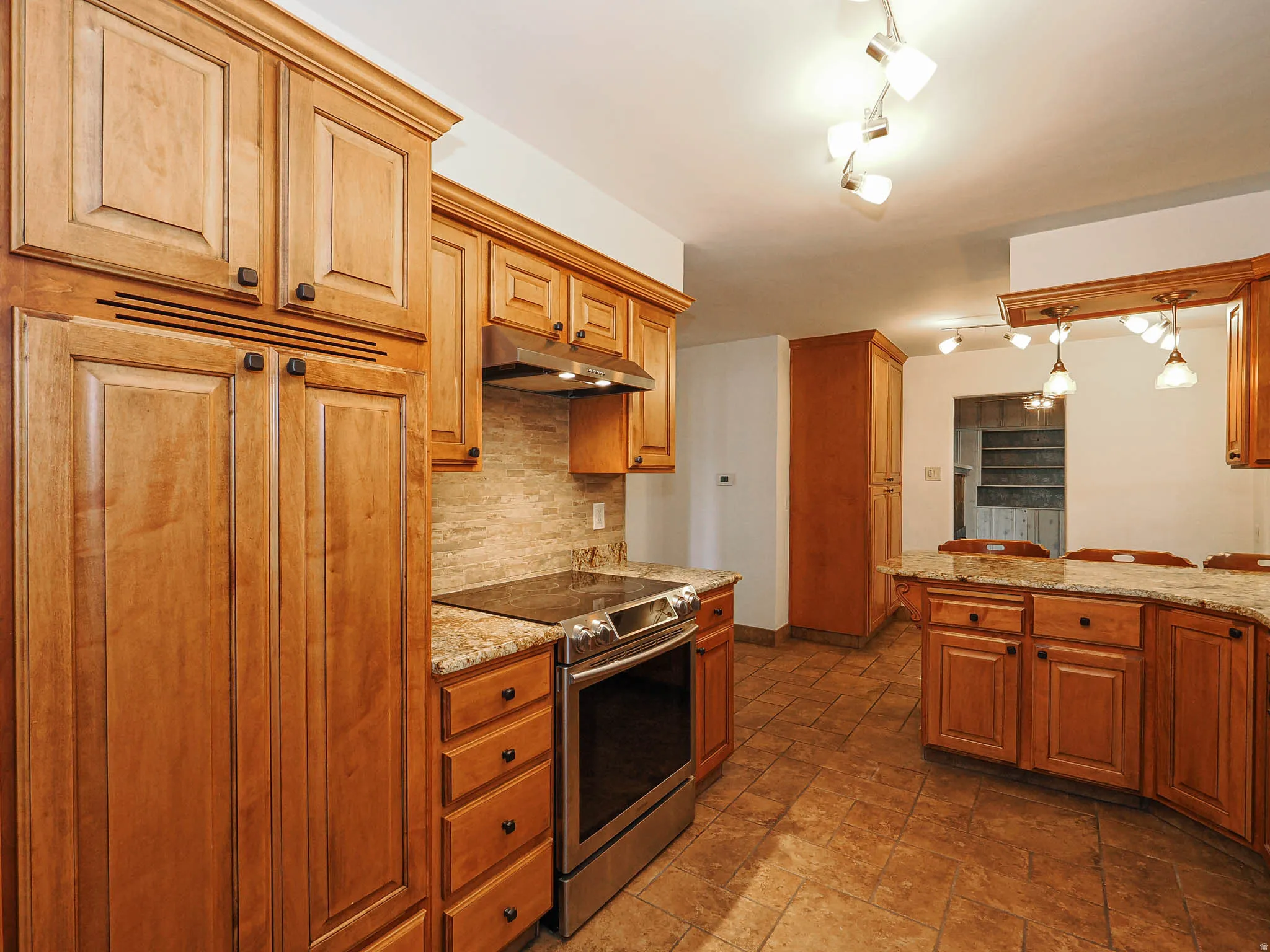Kitchen featuring wood cabinetry, granite countertops, stainless steel range, and tile flooring