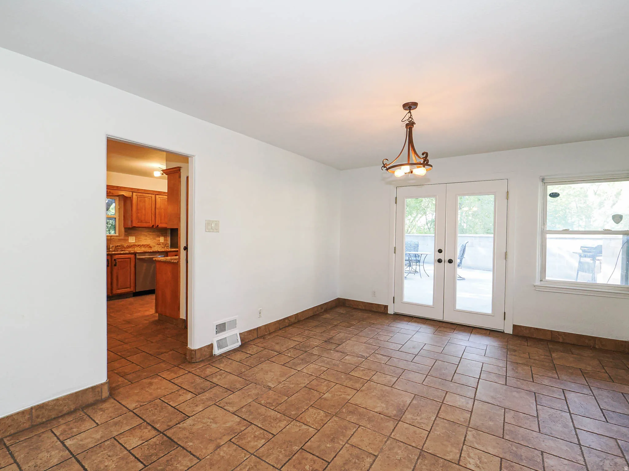 Dining area featuring patterned tile flooring, a decorative ceiling light fixture, and double glass-paneled doors opening to an outdoor patio
