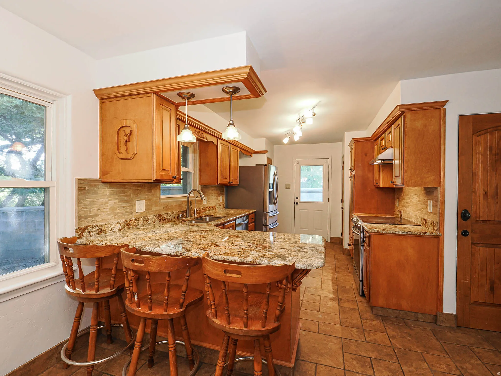 Kitchen featuring wood cabinetry, granite countertops, tile flooring, and stainless steel appliances