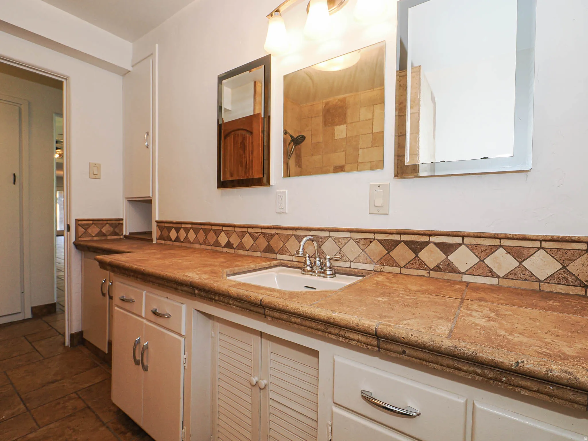 Bathroom vanity featuring a single basin sink, laminate countertop, and decorative tile backsplash