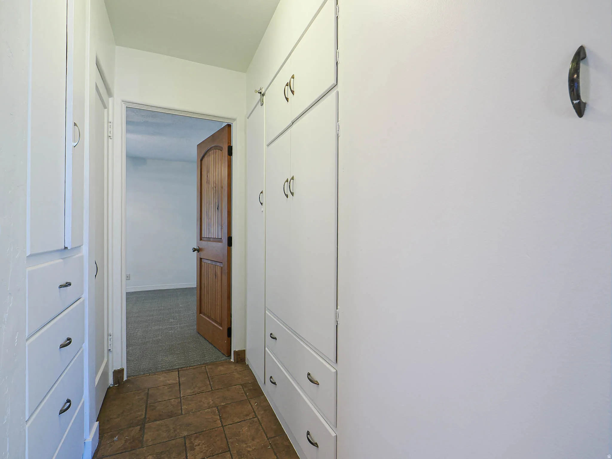 Hallway featuring extensive built-in cabinetry, tile flooring, and a wood-paneled door