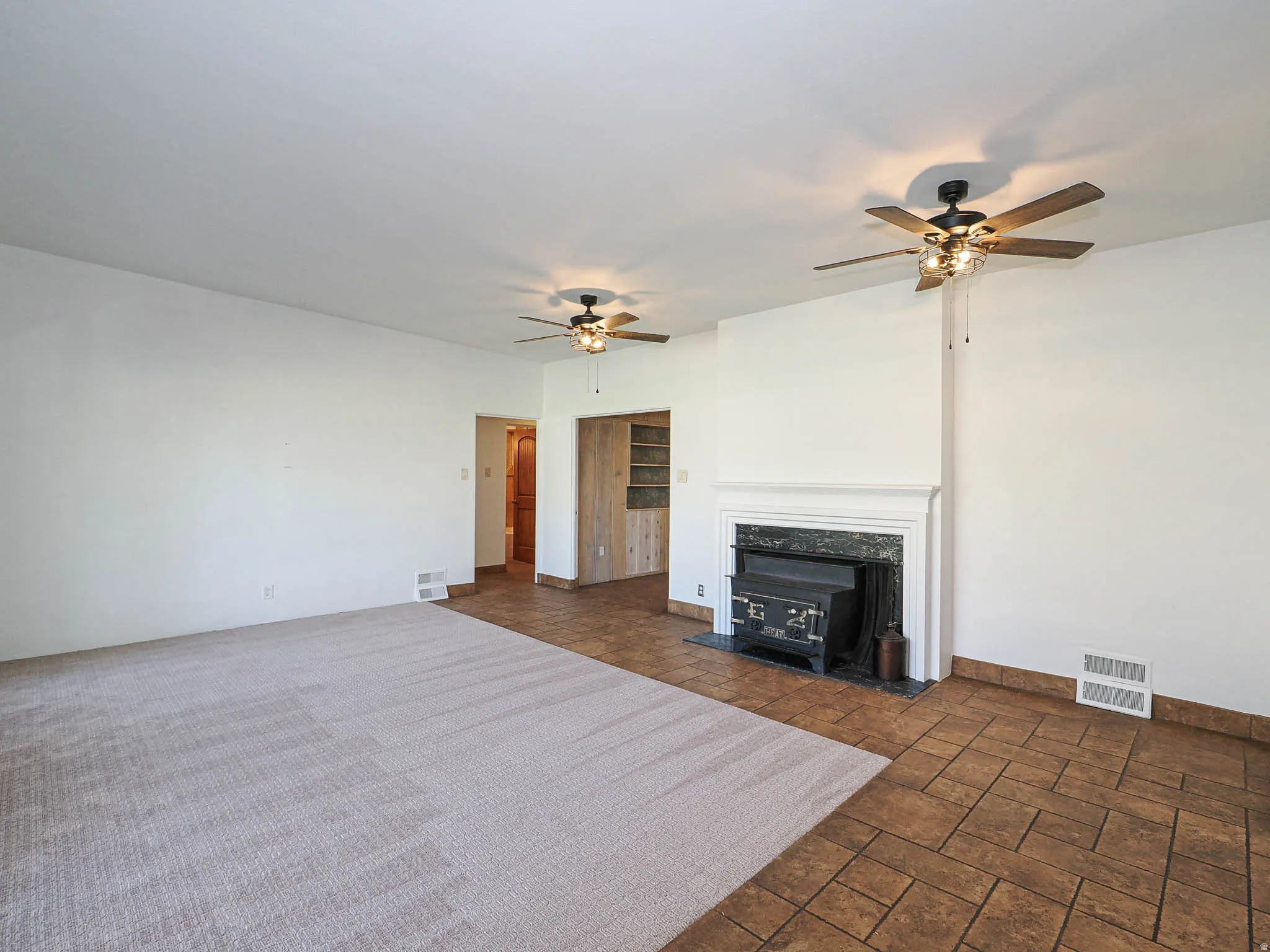 Spacious living area featuring a fireplace with a white mantel and wood stove insert