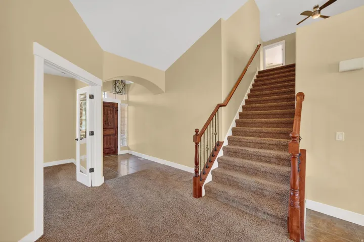 Entryway featuring a grand staircase with wood newel posts, wrought iron balusters, and carpeted treads