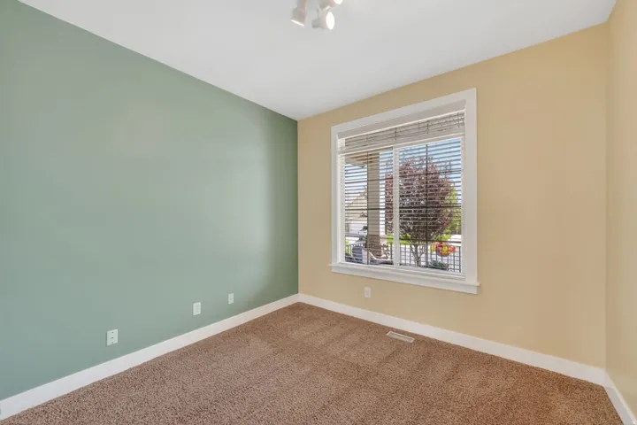 Room featuring a large window with white blinds, track lighting, and soft carpet flooring