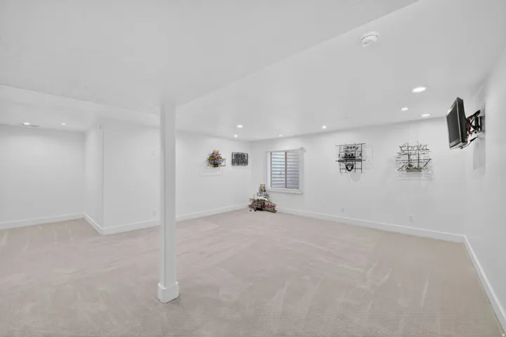 Spacious room featuring light-toned carpet flooring, recessed lighting, and a window with horizontal blinds