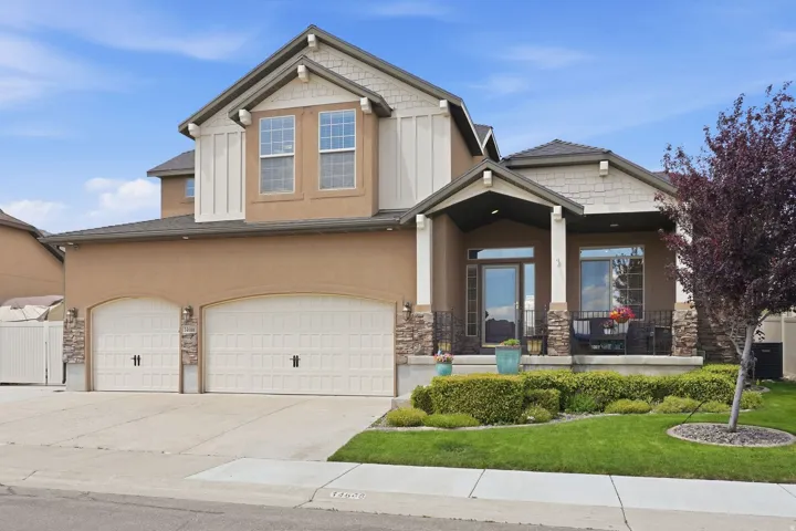 Two-story residence featuring a stucco and stone facade, covered front porch, and a three-car garage