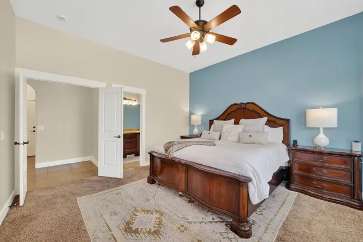 Carpeted Master bedroom featuring a vaulted ceiling and a wood-finish ceiling fan with integrated lighting