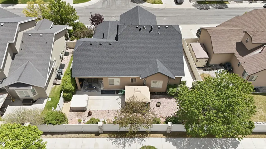 Private rear yard with a concrete patio, mature trees, and a stone-covered landscape bed