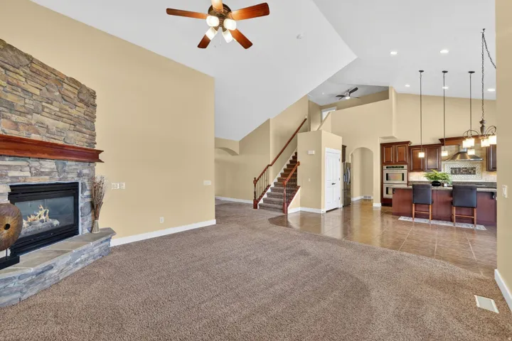 Spacious living area featuring vaulted ceilings and a stone-clad fireplace with a wood mantel
