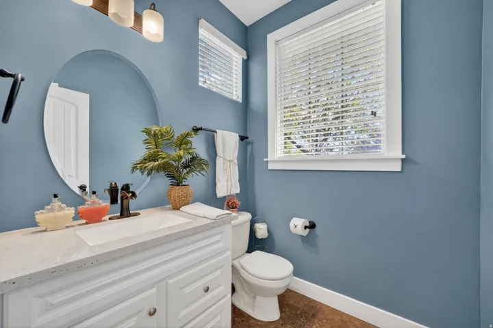 Bathroom vanity featuring a white rectangular sink with a bronze-finish faucet, framed by a large oval mirror
