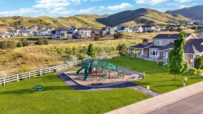 Community playground featuring multiple slides and climbing structures, bordered by a white picket fence