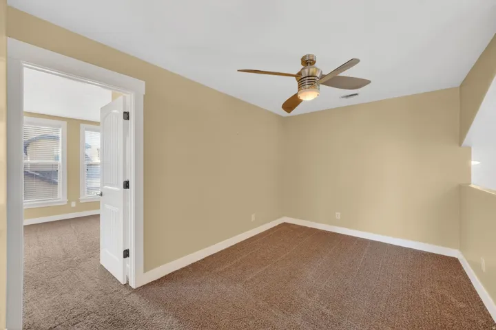 Upper landing featuring a ceiling fan with integrated lighting, a white paneled door with dark hardware, and light-toned walls